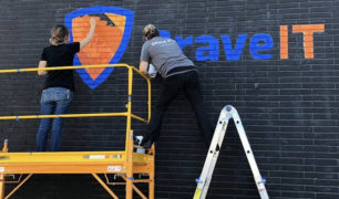NPB Studio artists painting Brave IT logo on wall