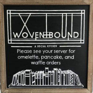 Chalkboard with text "Please see your server for omelette, pancake, and waffle orders" and image of shelf of books