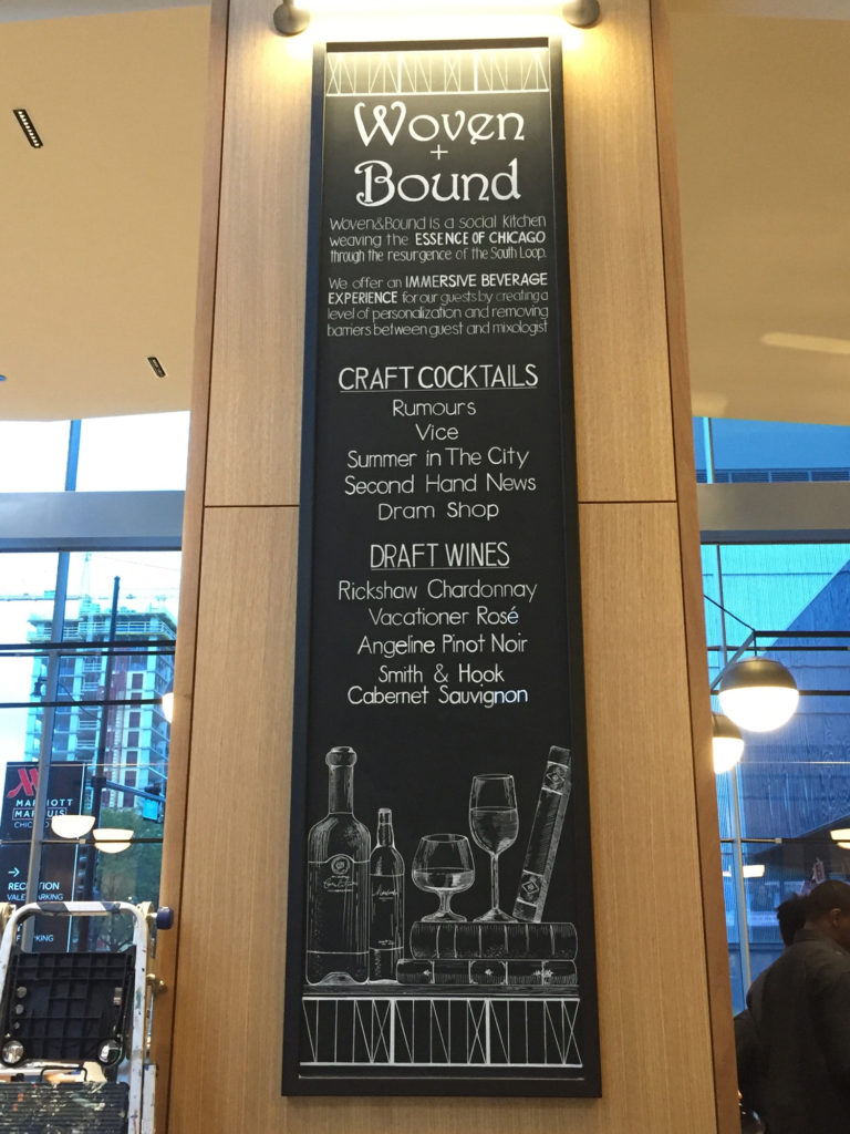 Woven + Bound chalkboard wine menu with images of wine bottles and glasses