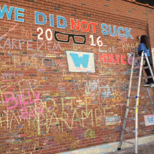 Nancy on ladder creating chalk art on the brick wall of Wrigley Field