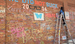 Nancy on ladder creating chalk art on the brick wall of Wrigley Field