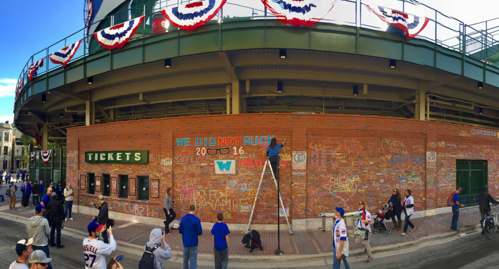 Panorama of Nancy creating chalk art on the brick wall of Wrigley Field